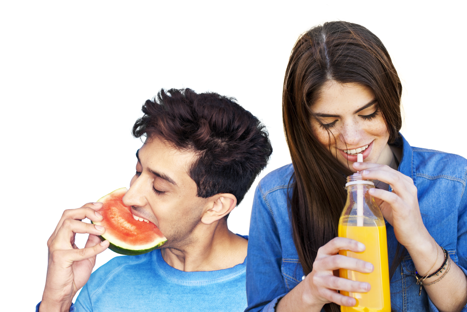 Un homme qui mange une pastèque et une femme qui boit un jus d'orange